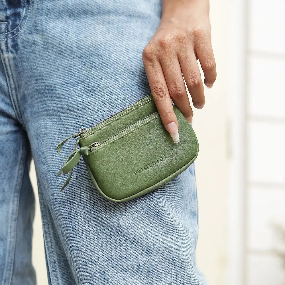 Green wallet held by a person wearing blue jeans
