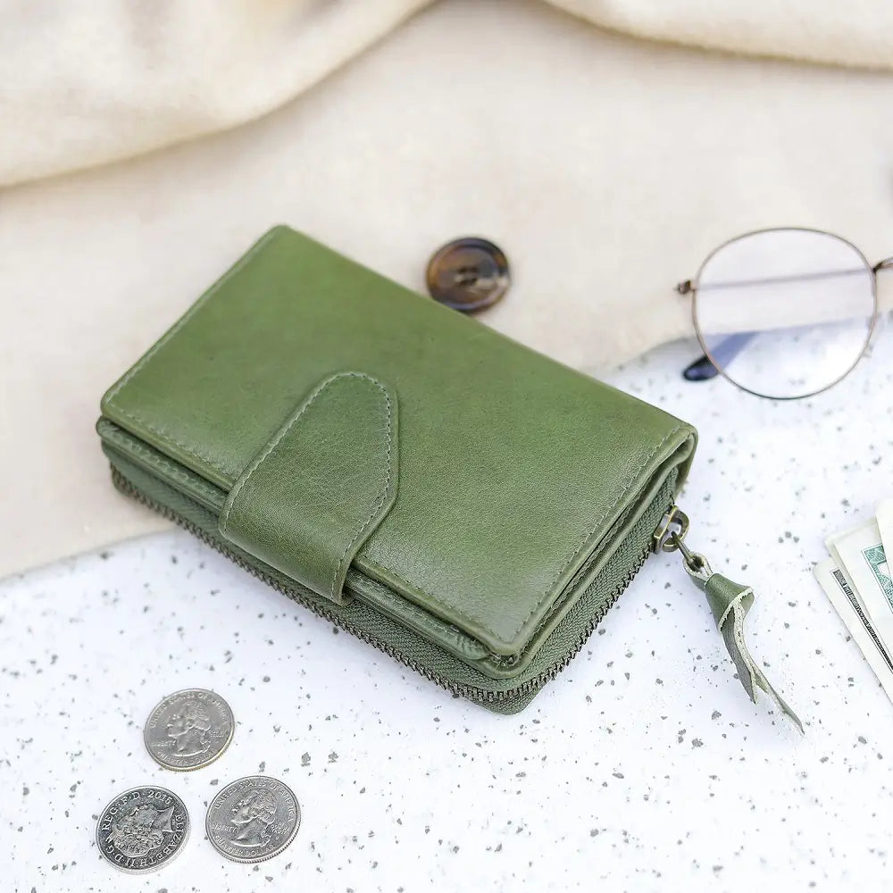 Green wallet on a textured surface with coins and glasses