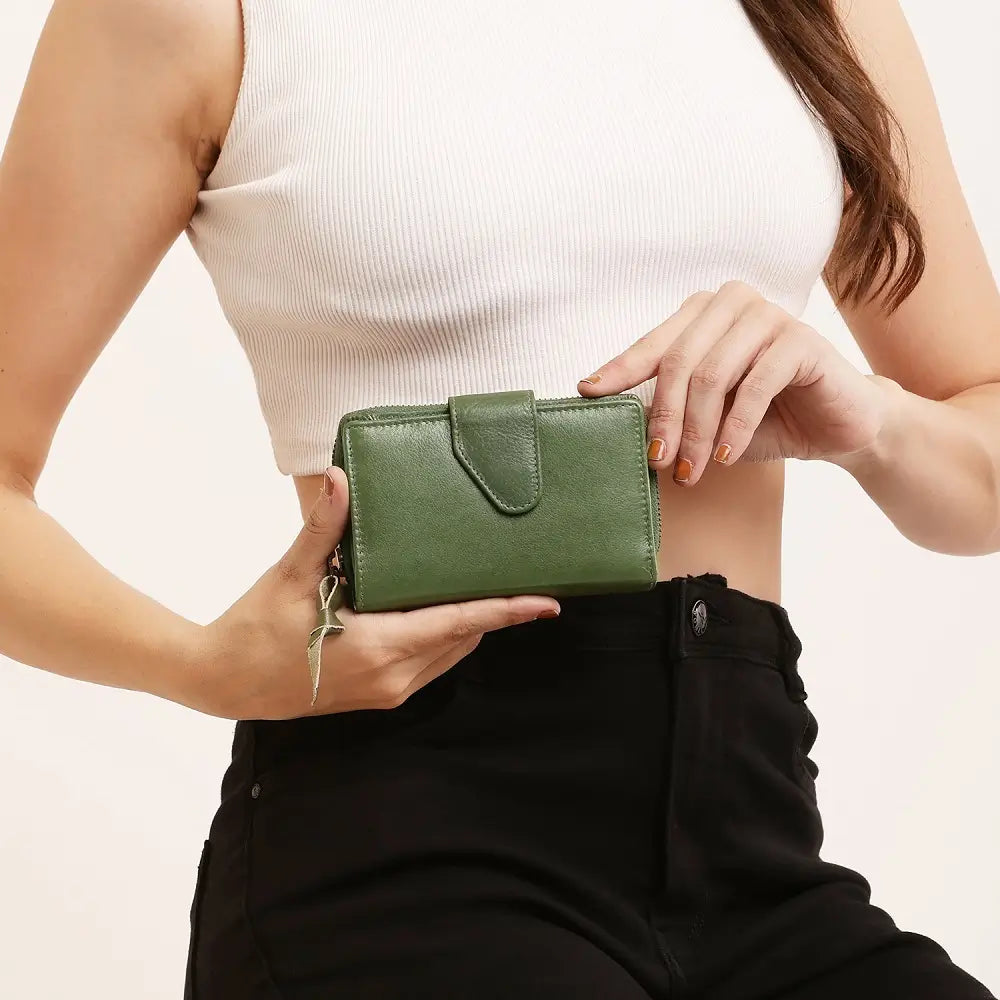 Person holding a green wallet against a neutral background