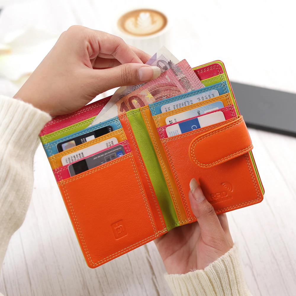 Green wallet with cards and money held by a person, blurred background