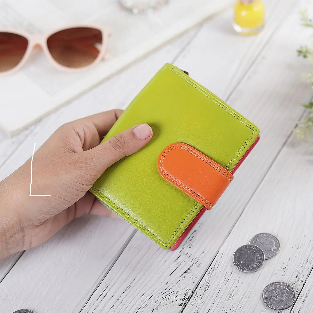 Person holding Green wallet with multiple card slots held by hands on a light wooden surface.
