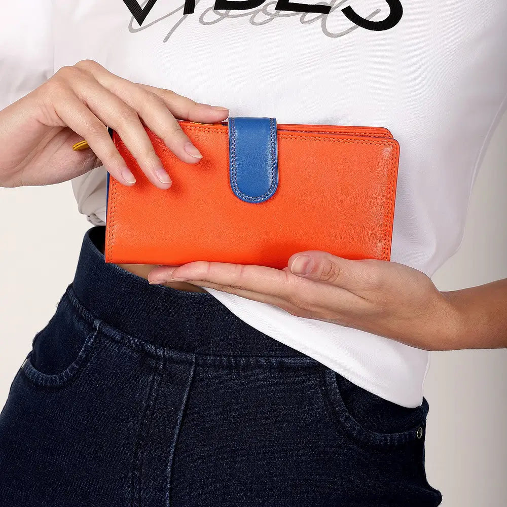 Person holding an orange wallet with a blue strap against a white background