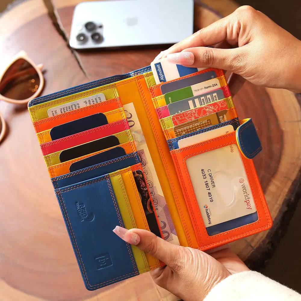 Orange wallet with multiple card slots held by a hand on a wooden surface.