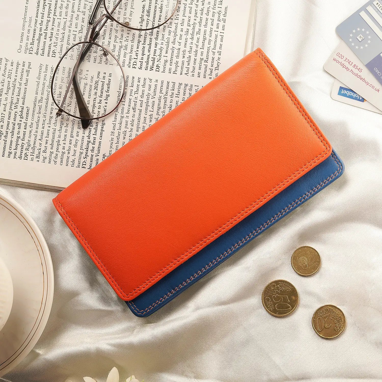 Lifestyle view of orange wallet with blue bottom section on a white background 