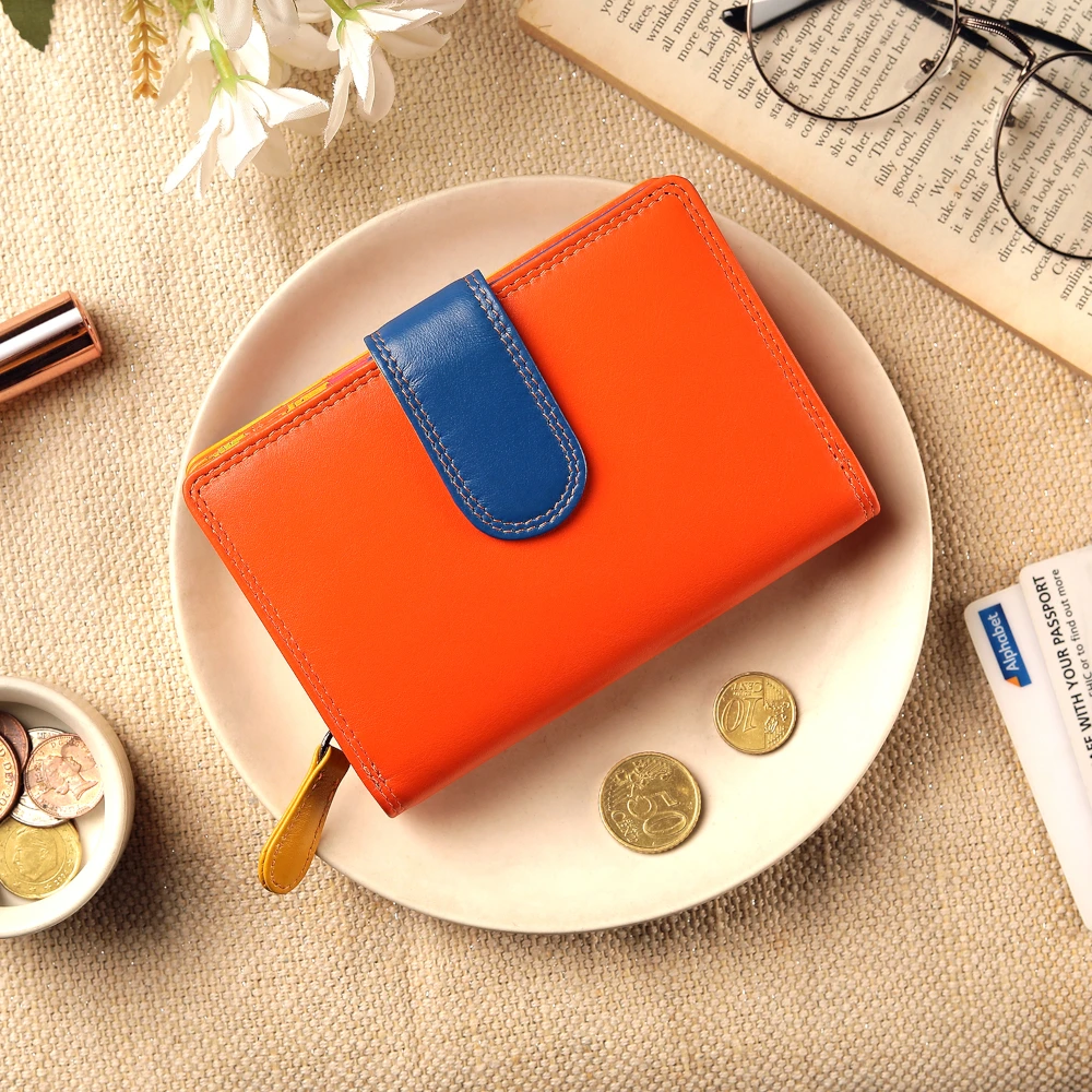 Orange wallet with blue flap on a white plate, surrounded by coins and a book.
