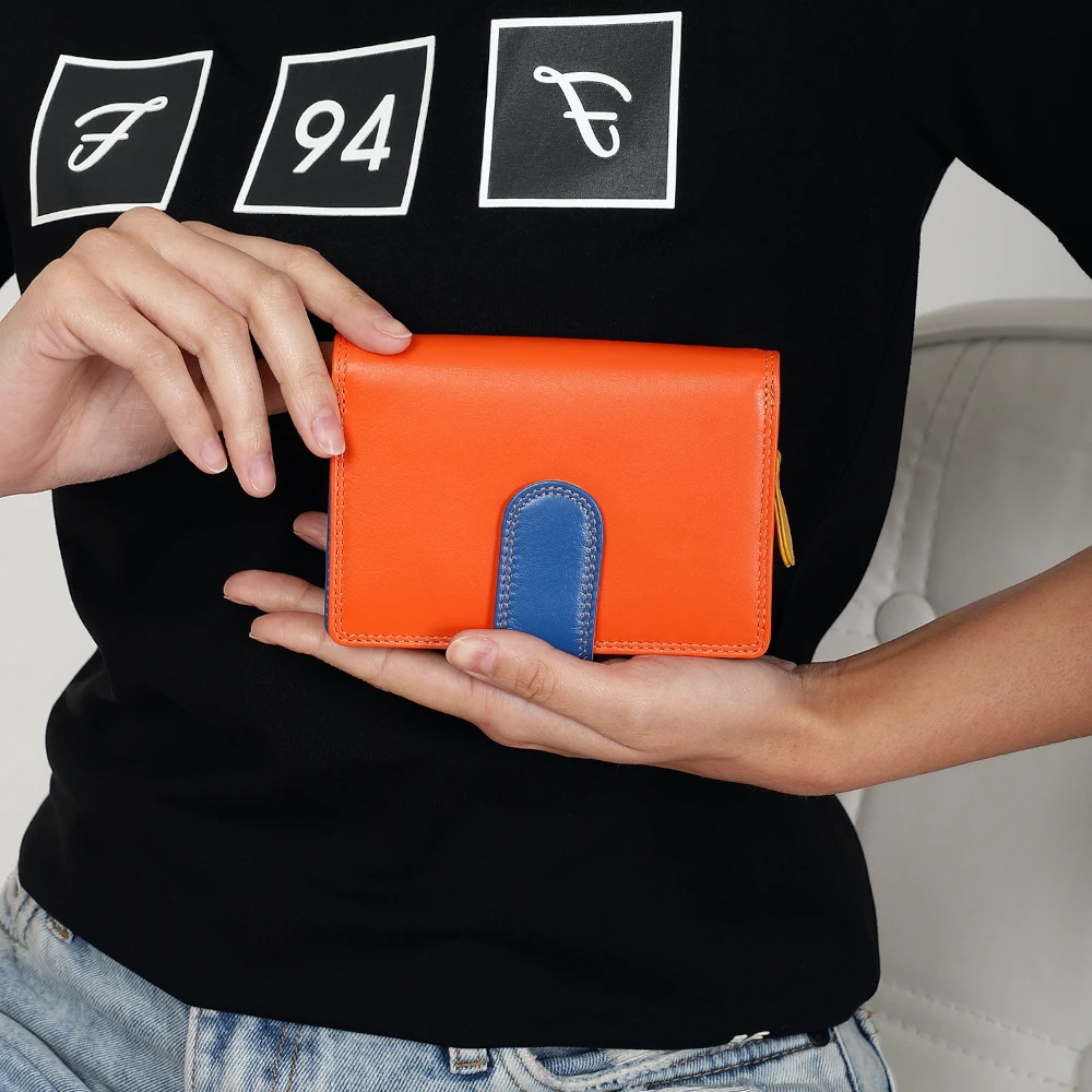 Person holding an orange and blue wallet with a black shirt and jeans in the background