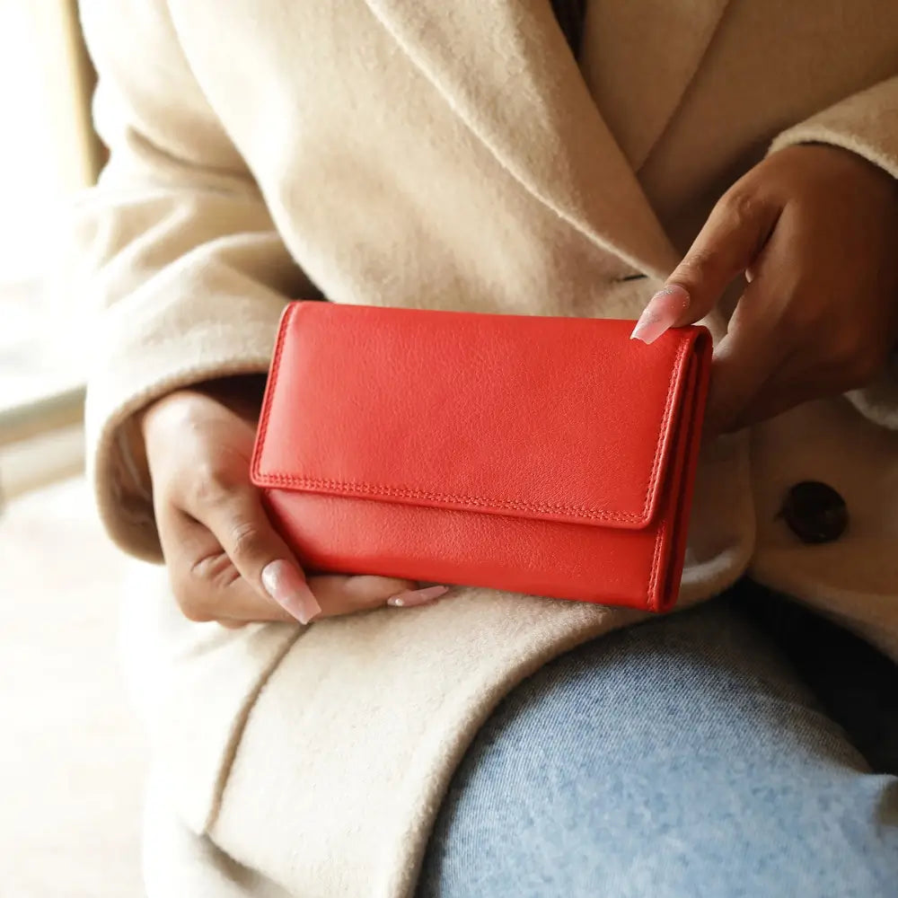 Person holding a Orange wallet with a beige coat and blue jeans