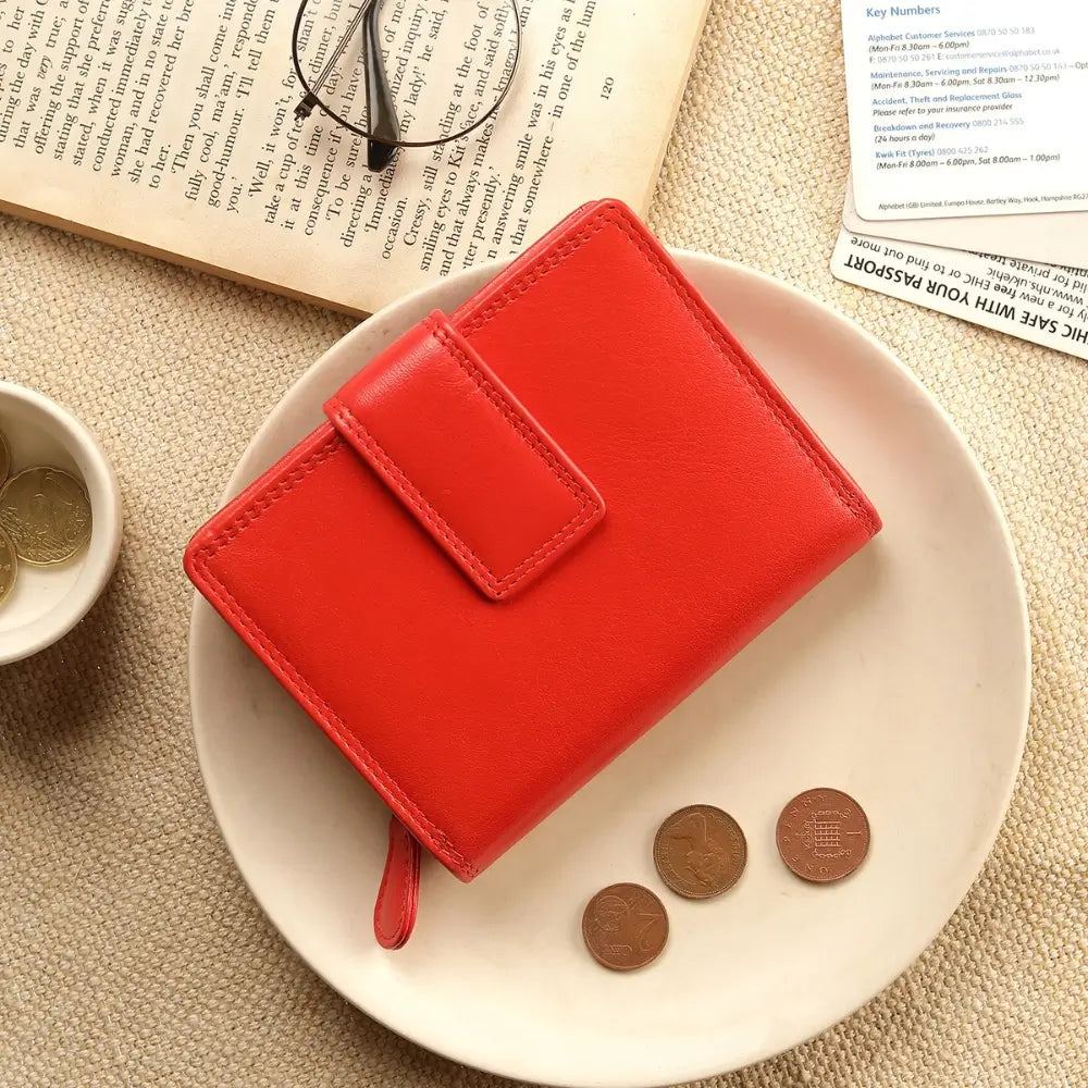 Orange wallet on a white plate with coins and glasses on a book