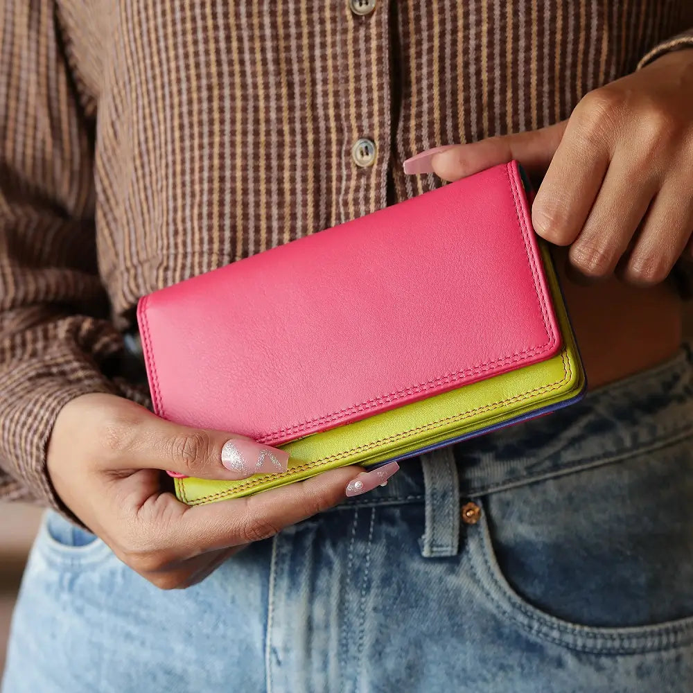 Person holding Pink wallet with green bottom section on a white background