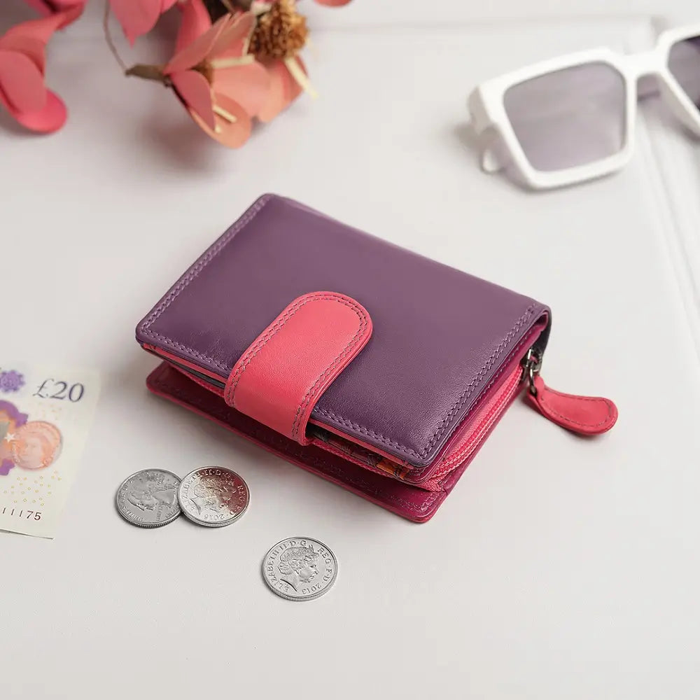 Purple  wallet with coins and a banknote on a light surface.