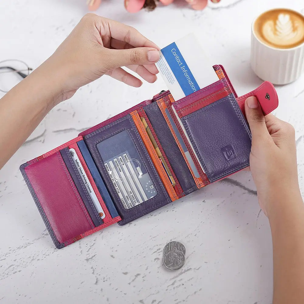 Person opening a  purple wallet with various cards and a coin on a white surface.