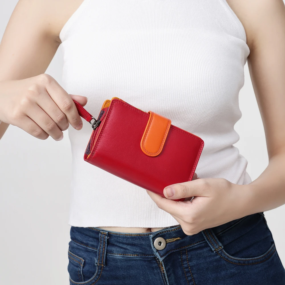 Person holding a red wallet with an orange flap against a white background