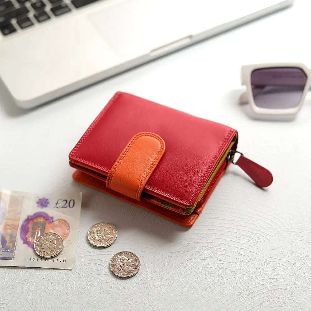 Red wallet with orange accent on a white surface with coins and money.