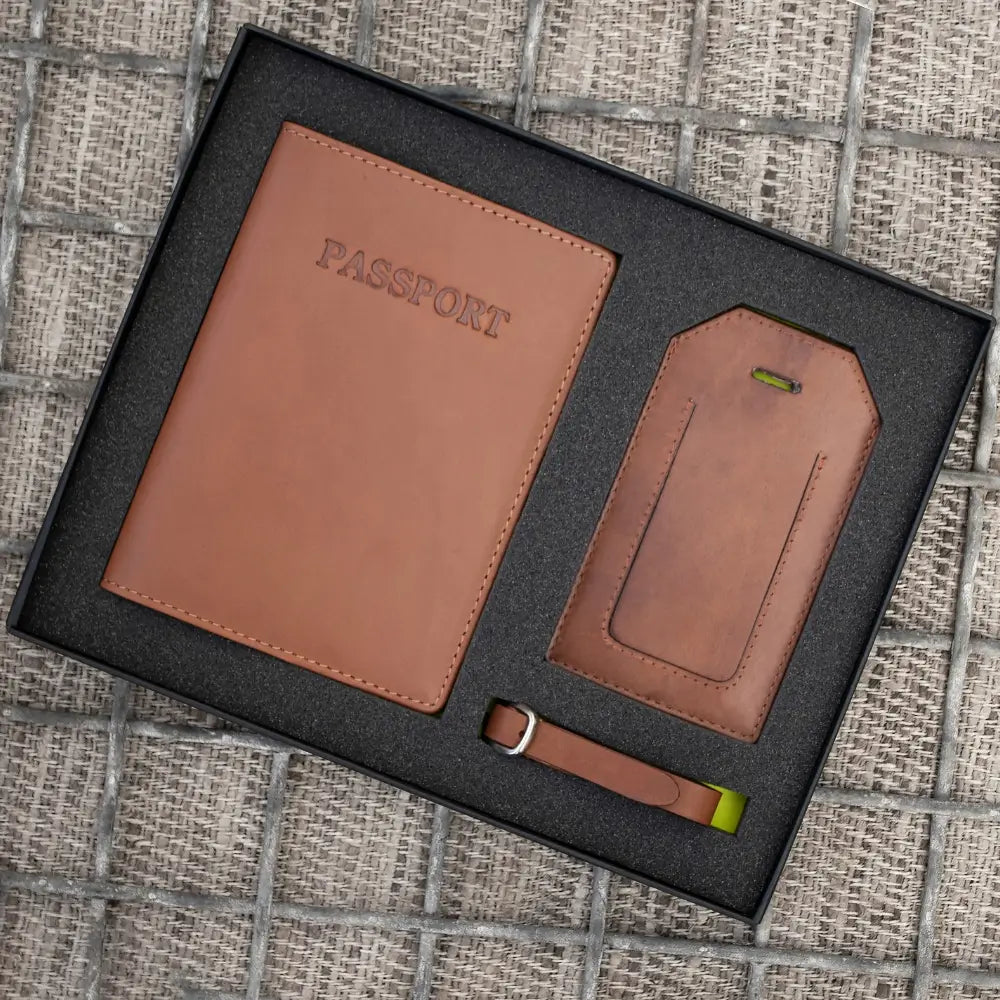 Brown leather passport holder and luggage tag set on a textured surface