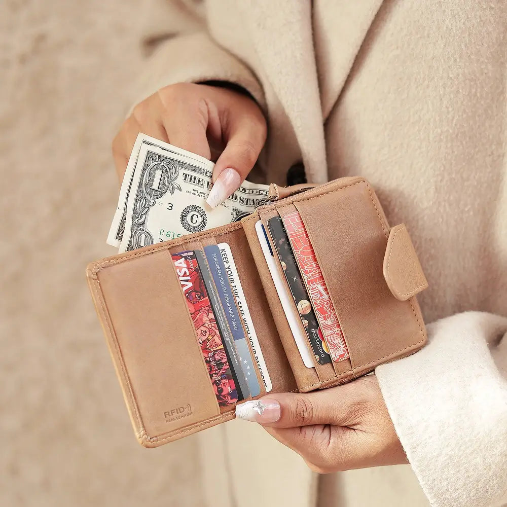 Person holding a sand wallet with money and cards against a neutral background