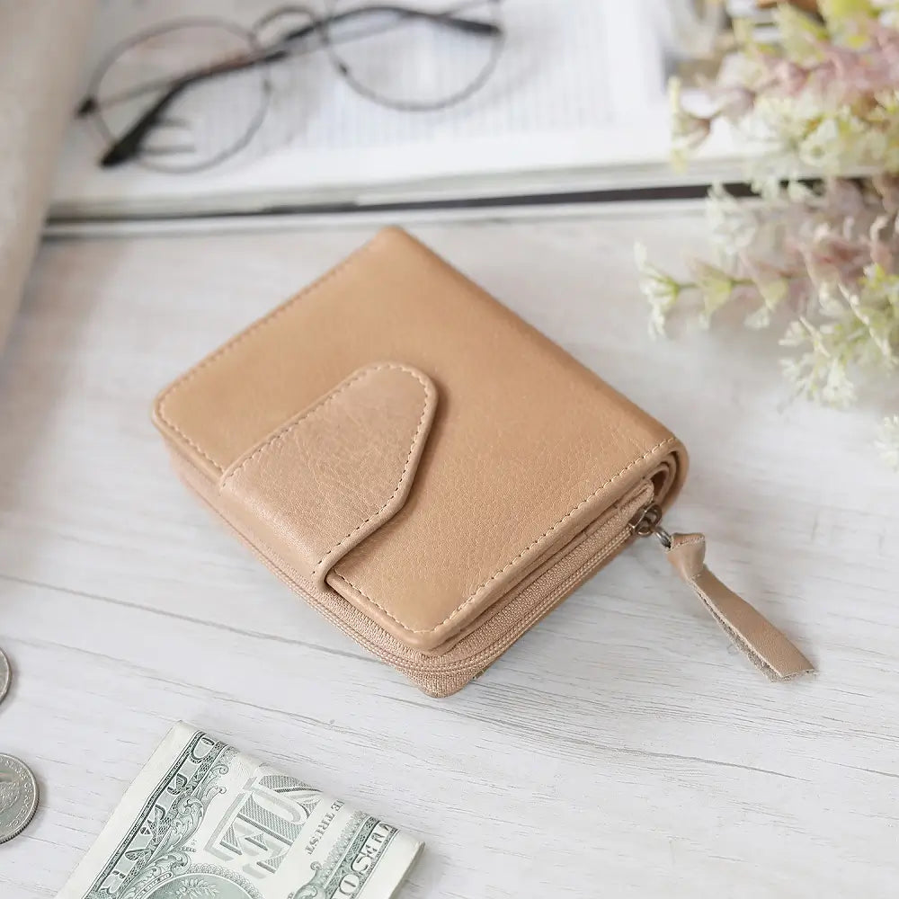 sand wallet on a light wooden surface with money and glasses in the background