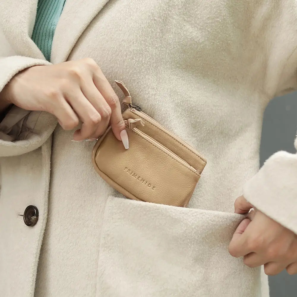 Person placing a Sand wallet into a beige coat pocket