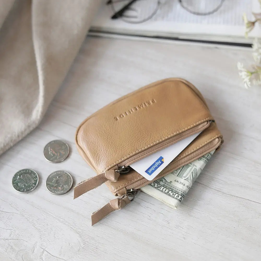 Sand  leather wallet with coins and money on a light wooden surface