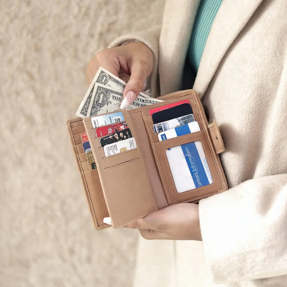 Person holding a sand wallet with money and cards against a neutral background