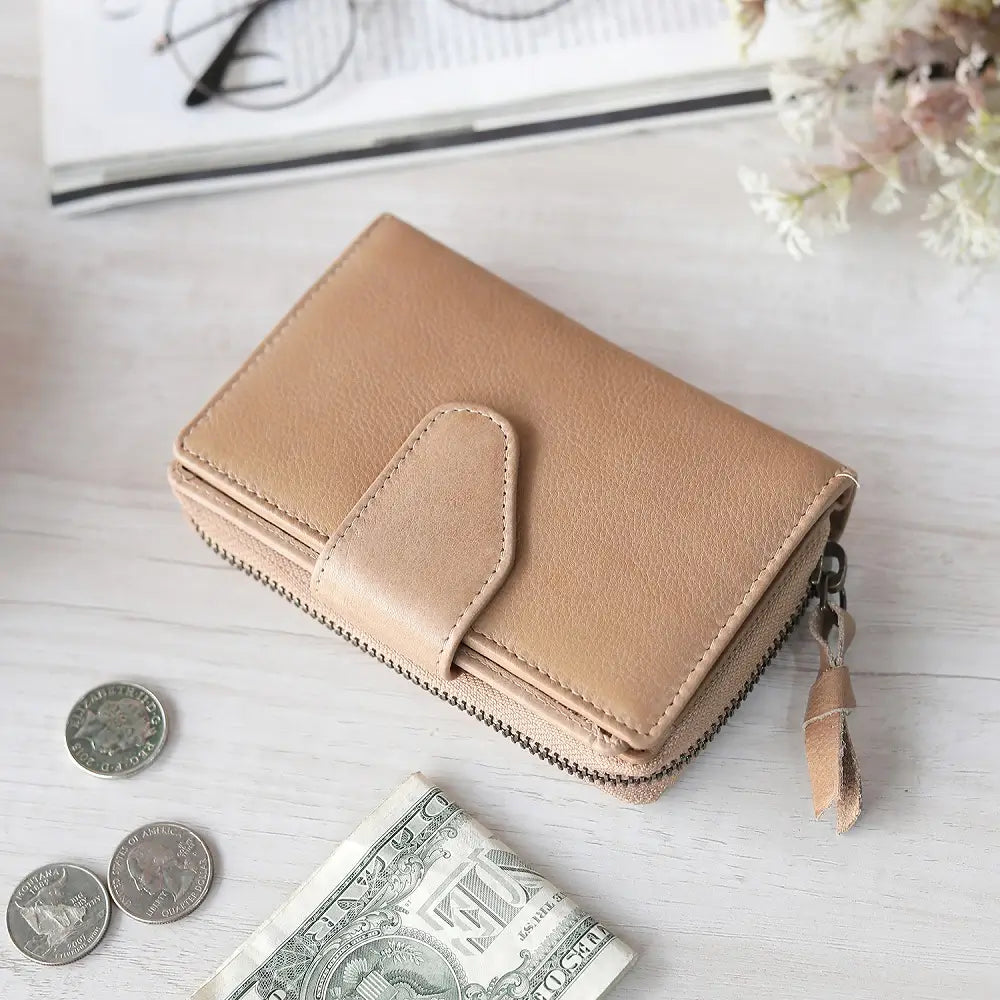 Sand wallet with coins and a dollar bill on a light wooden surface