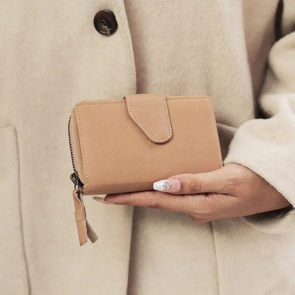 Person holding a sand wallet against a beige coat background