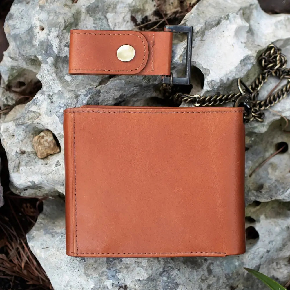 Tan leather wallet with chain on a rocky surface
