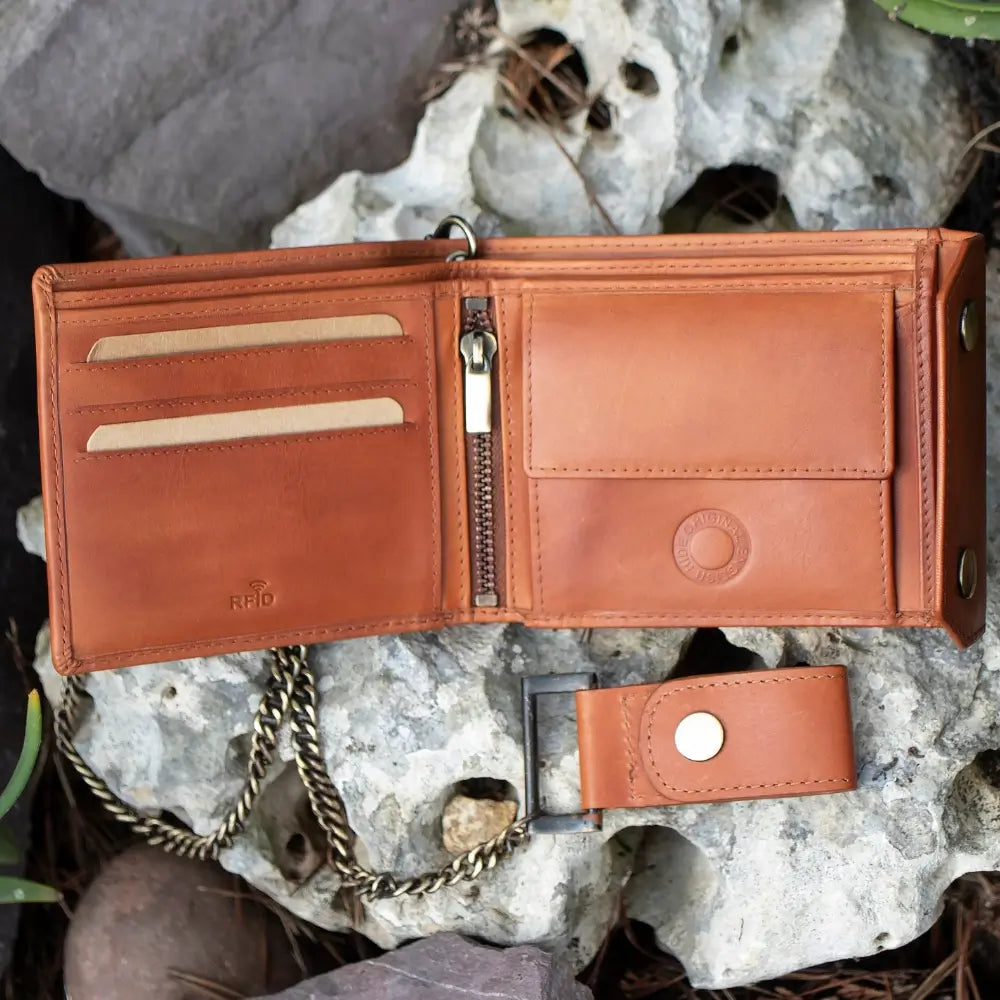Tan leather wallet with chain on a rocky surface