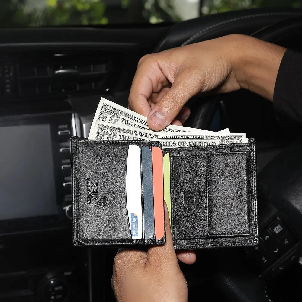 Person holding a black wallet with money and cards inside, sitting in a car.