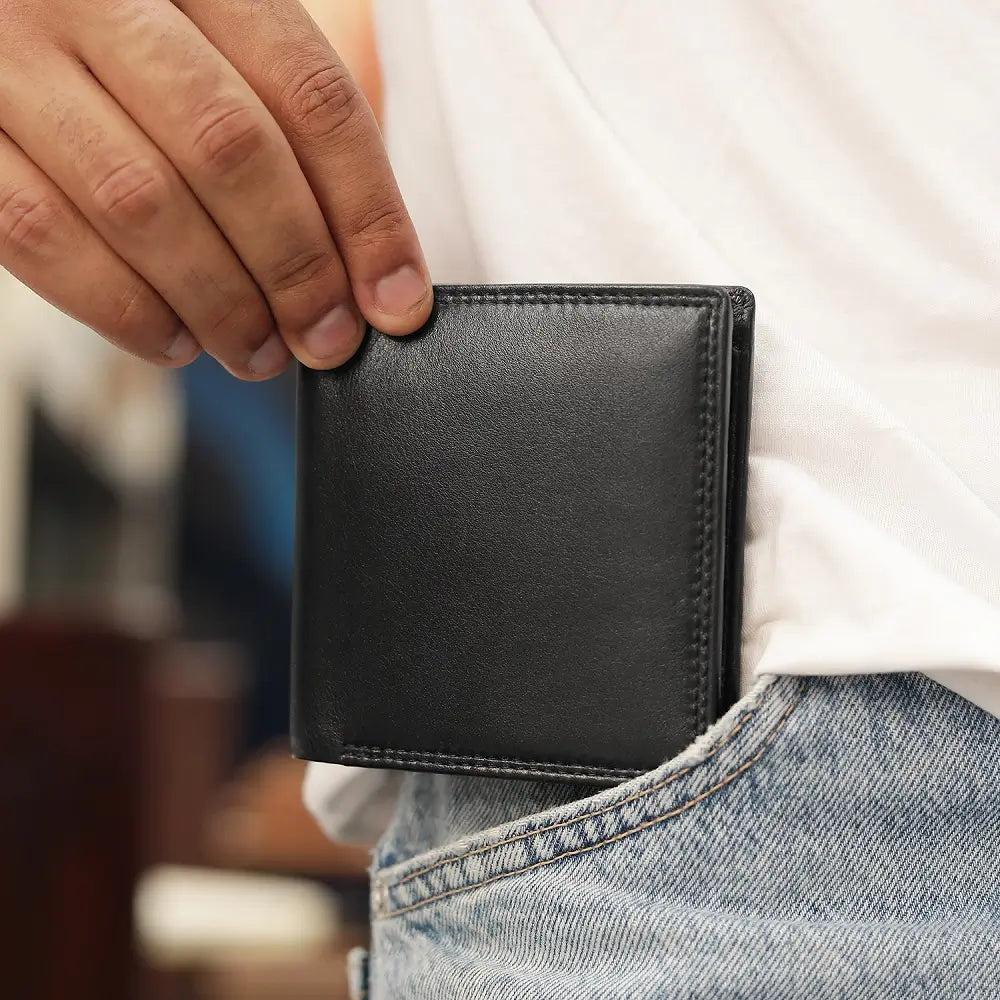 Person holding a black leather wallet with a blurred background