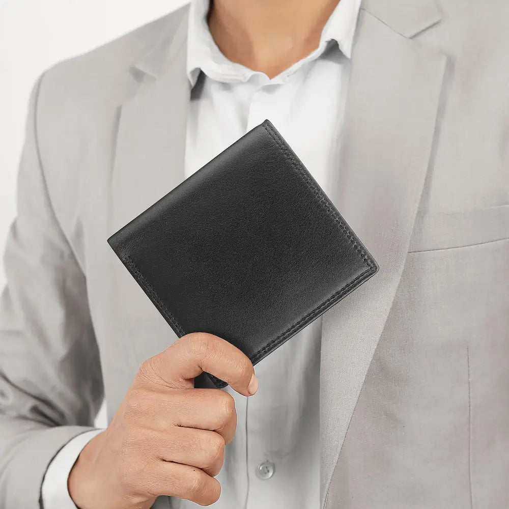 Person holding a black leather wallet against a light gray suit background