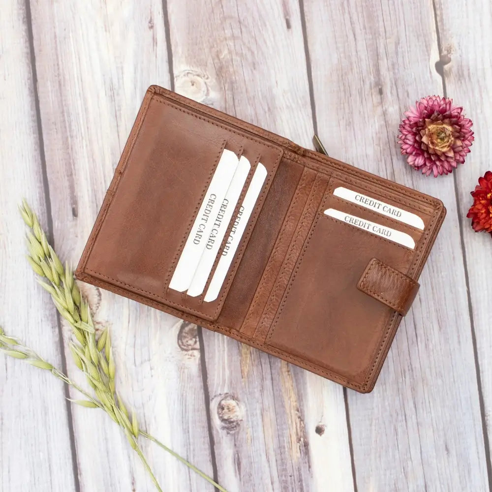 Brown leather wallet with card slots on a wooden surface with flowers.