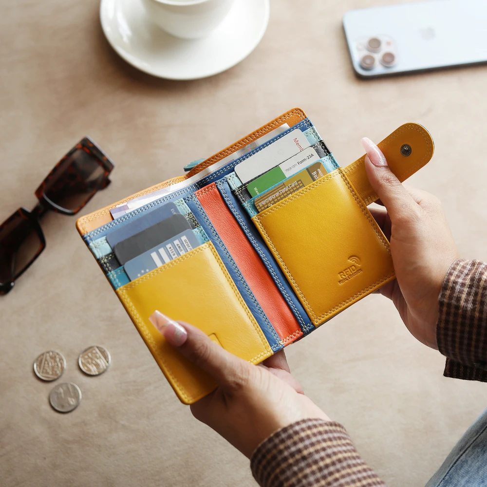 Hand holding a yellow wallet with cards and coins on a table.