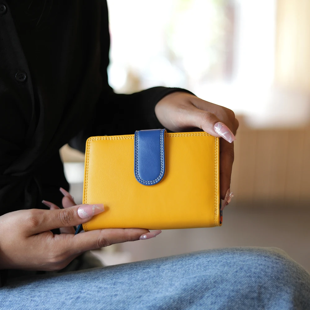 Person holding a yellow wallet with a blue flap
