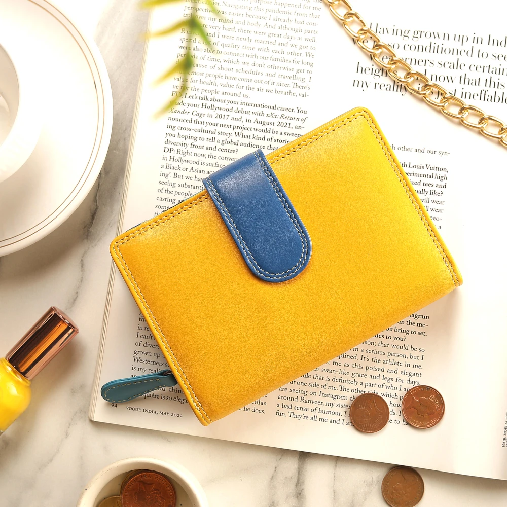 Yellow wallet with blue flap on an open book with coins and a cup in the background