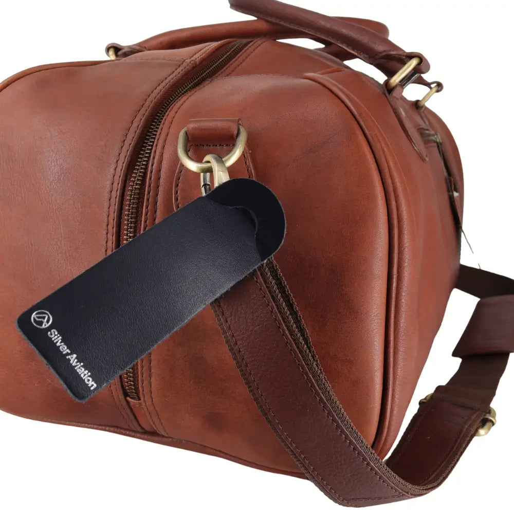Close-up of a brown leather bag with a black tag and gold hardware.