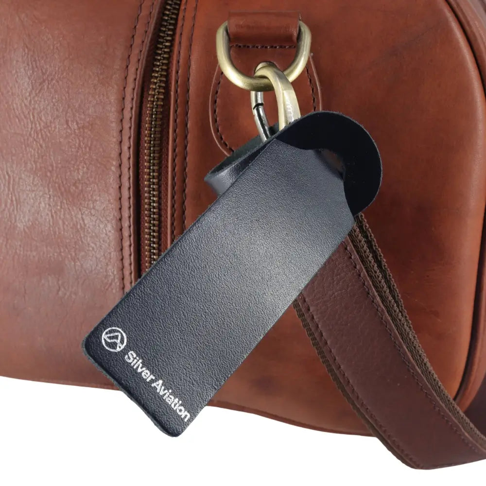 Close-up of a brown leather bag with a black tag and gold hardware.