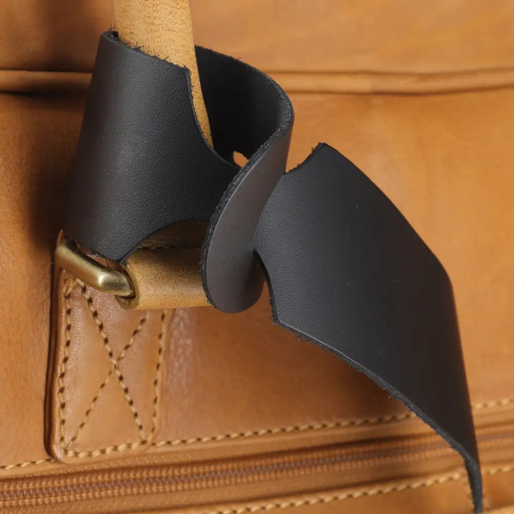 Close-up of a brown leather bag with a black tag and gold hardware.