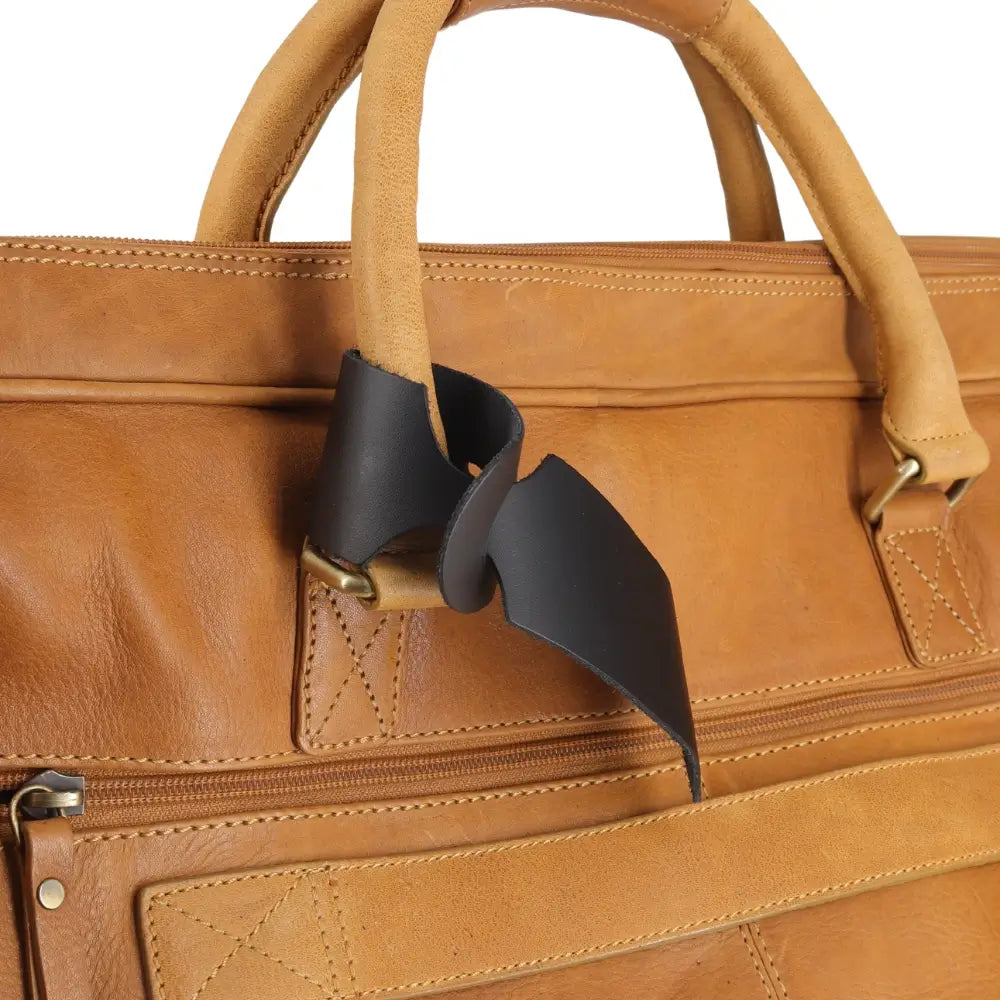 Close-up of a brown leather bag with a black tag and gold hardware.