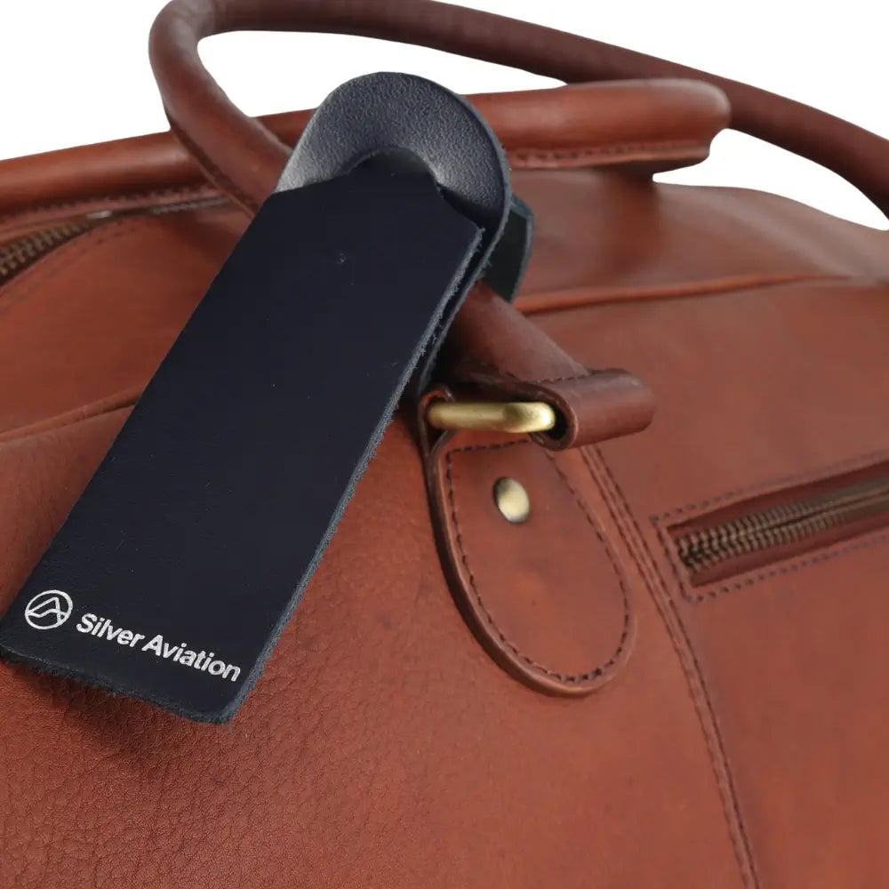 Brown leather bag with a black tag featuring 'Silver Aviation' on a white background