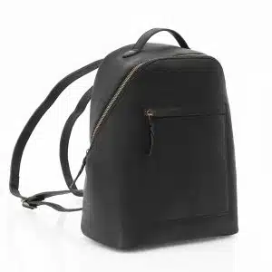 a black leather backpack viewed from a side angle. The backpack has a brassed coloured zip to the main section.