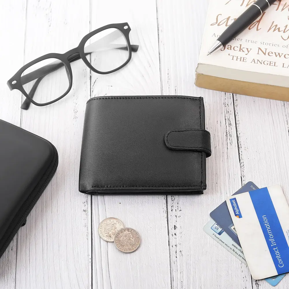 Flat lay of Basic Wallet Style 99 black leather RFID bifold wallet with tab closure, shown with coins, cards, and glasses