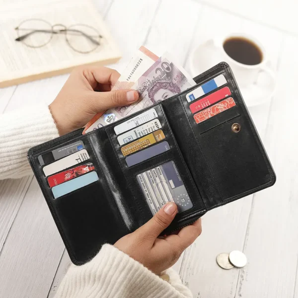 A person opening the black zip-around leather purse, revealing multiple card slots, an ID window, and cash.