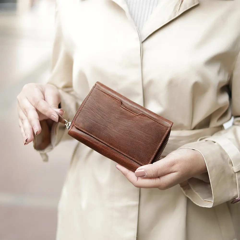 A compact and practical brown zip-around leather purse, designed for versatility and durability, displayed in hand.