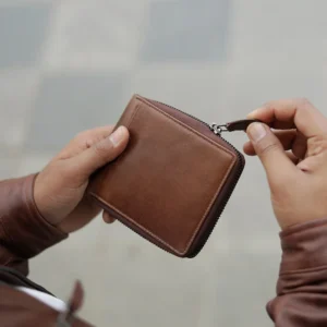 Man holding brown leather zip-around wallet - Alperto 4257, showcasing durable zip closure and compact design.