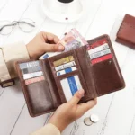 A person opening the brown zip-around leather purse, revealing multiple card slots, an ID window, and cash.