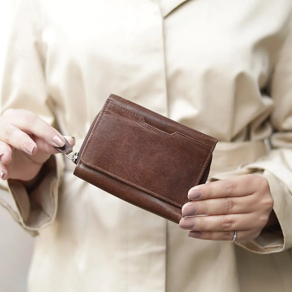 User holding the Medium brown Trifold Purse in hand, highlighting its compact size and practical functionality for everyday use.