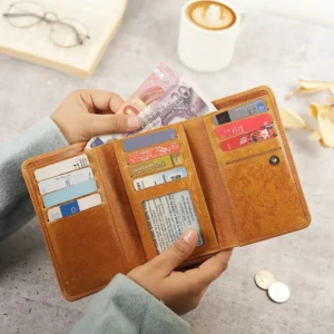 A person opening the tan zip-around leather purse, revealing multiple card slots, an ID window, and cash.