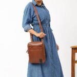 Brown Tuscan leather messenger bag with adjustable crossbody strap, shown worn over shoulder.