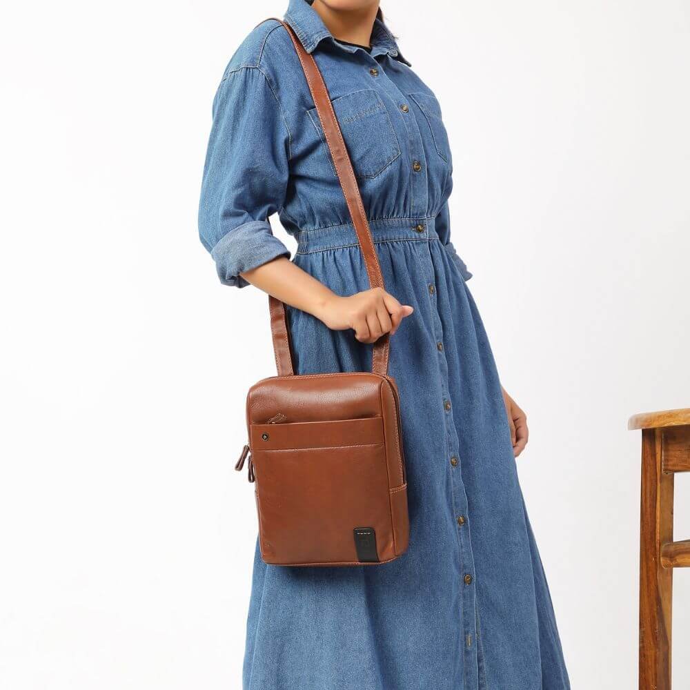Brown Tuscan leather messenger bag with adjustable crossbody strap, shown worn over shoulder.