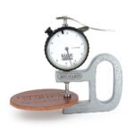 A Milhard dial thickness gauge measuring a round piece of brown leather labeled ‘Espresso Martini,’ showing a reading of approximately 4.4 millimeters on the dial.